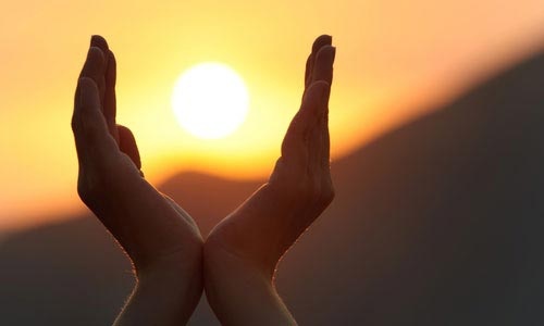 photo de deux mains autour du soleil