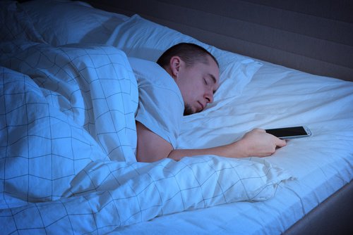 homme avec son portable au lit