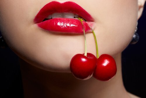 femme tenant des cerises dans sa bouche