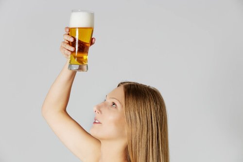 Femme qui tient un verre de bière pour la chevelure