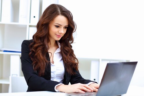 femme sur son ordinateur assise à un bureau
