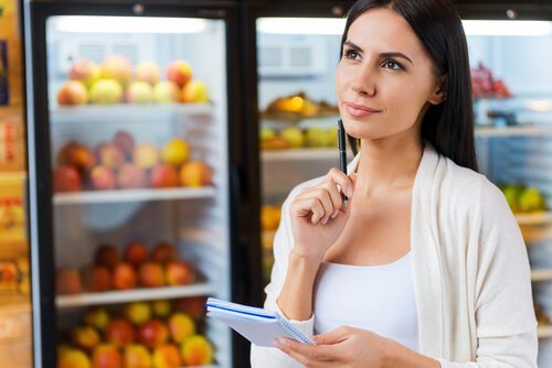 Fruits dans un frigo et femme qui prépare une liste de courses