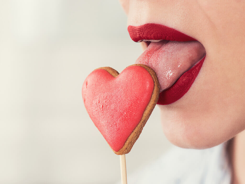 femme léchant une sucette en forme de coeur