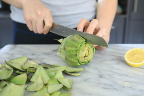 Femme qui coupe un artichaut