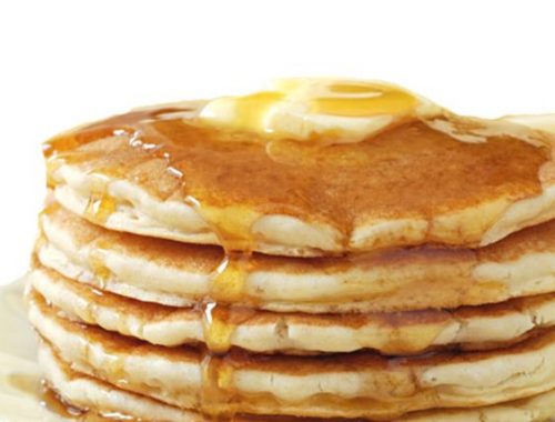 Des pancakes servis avec du miel et une banane