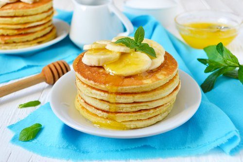 Des pancakes servis avec du miel et une banane