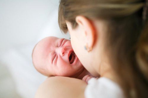 Un bébé qui pleure dans les bras de sa mère