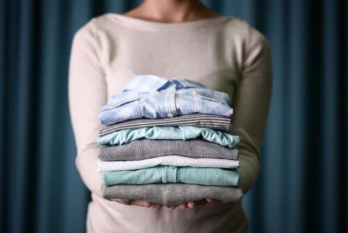 Femme qui porte une pile de vêtements