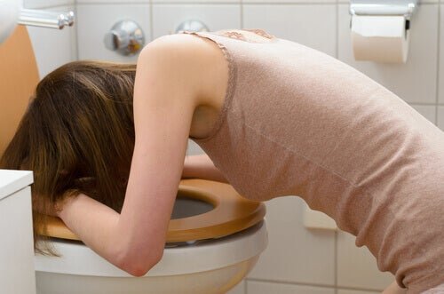 Une femme qui vomit dans la cuvette à cause de la diaboulimie