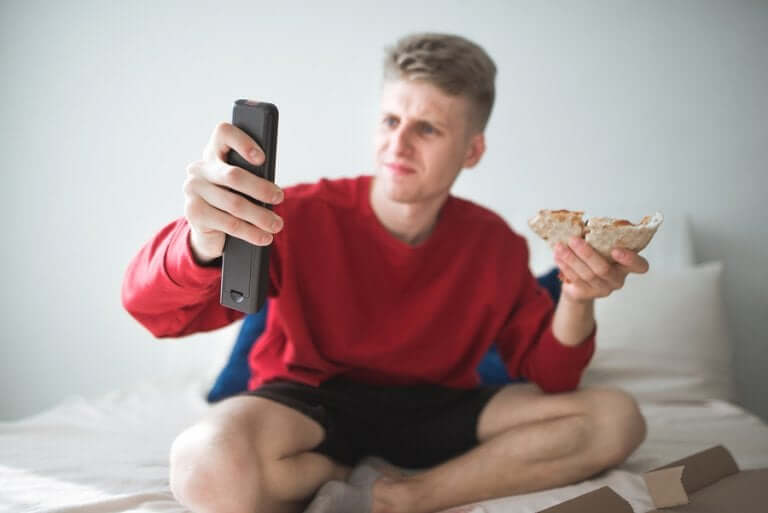 Un homme devant la télé avec une part de pizza représente le sédentarisme