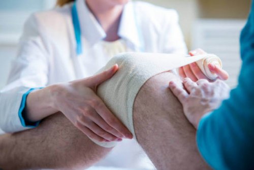 Un médecin applique des bandages sur le genou