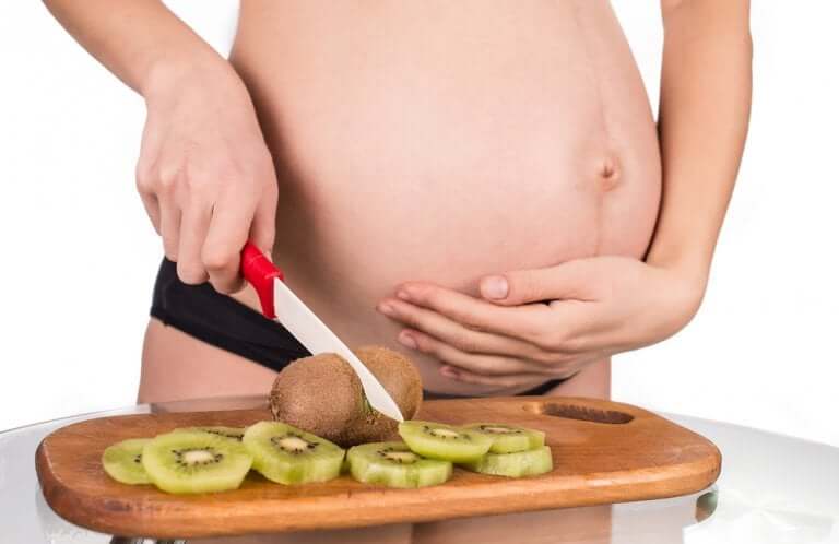 Une femme enceinte en proie au manque d'appétit coupant un kiwi