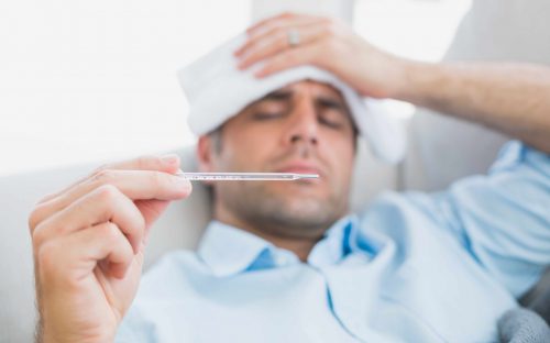 Un homme ayant la grippe prenant sa température