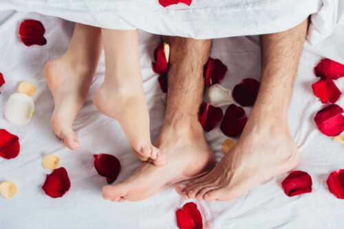 Un couple dans un lit couvert de pétales de roses pour sa nuit de noces