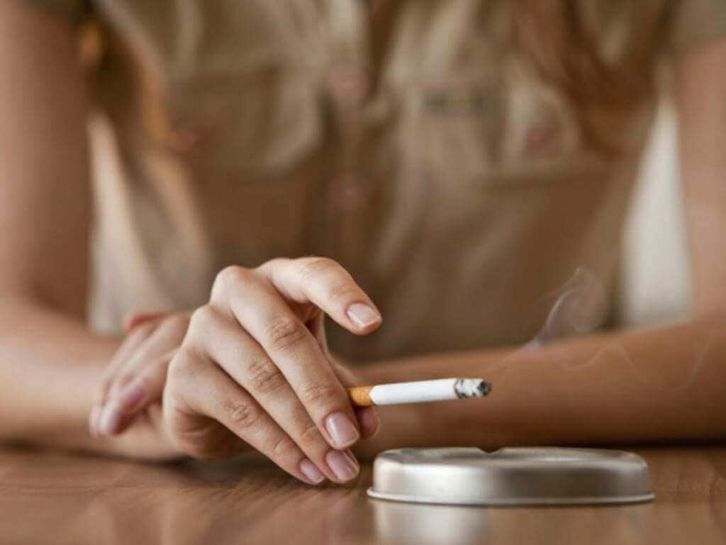 Une femme en train de fumer, ce qui a un impact sur sa santé respiratoire