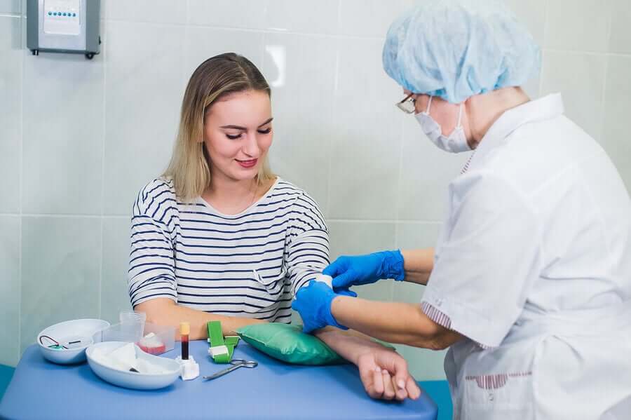 Un médecin faisant une prise de sang à une femme guérie du coronavirus