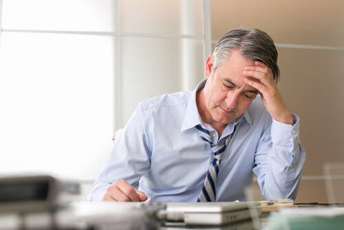 Un homme stressé au travail ayant des cheveux blancs
