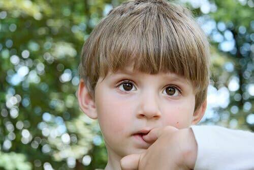 Un enfant met les doigts dans sa bouche.
