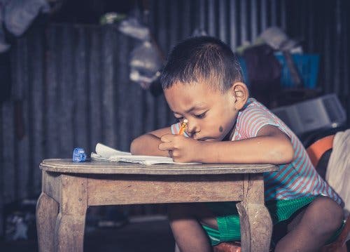 Un jeune garçon en train d'écrire sur une table