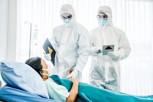 Des médecins qui portent des EPI examinant un patient
