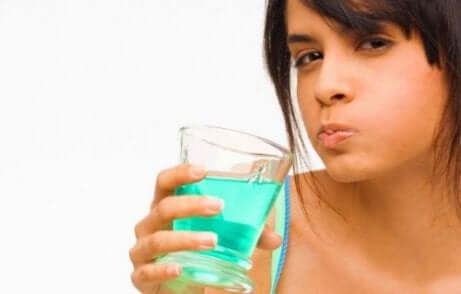 Une femme faisant un bain de bouche avec de la chlorhexidine.