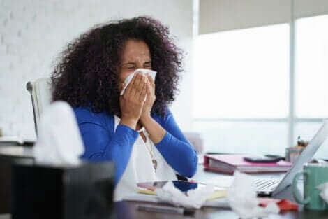 Une femme qui se mouche touchée par la grippe.