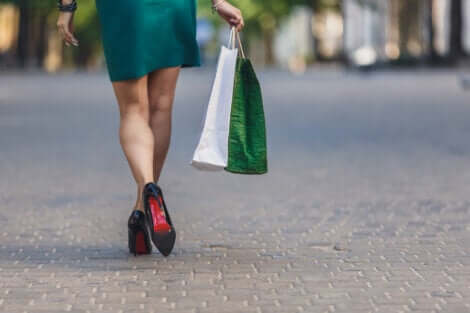 Une femme victime de dépendance au shopping qui marche avec des sacs dans la main.