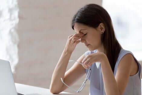 Une jeune femme qui fait du télétravail, se frotte les yeux.