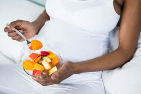 Une femme enceinte qui mange des fruits.