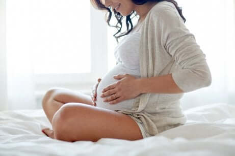 Une femme enceinte qui se touche le ventre. 