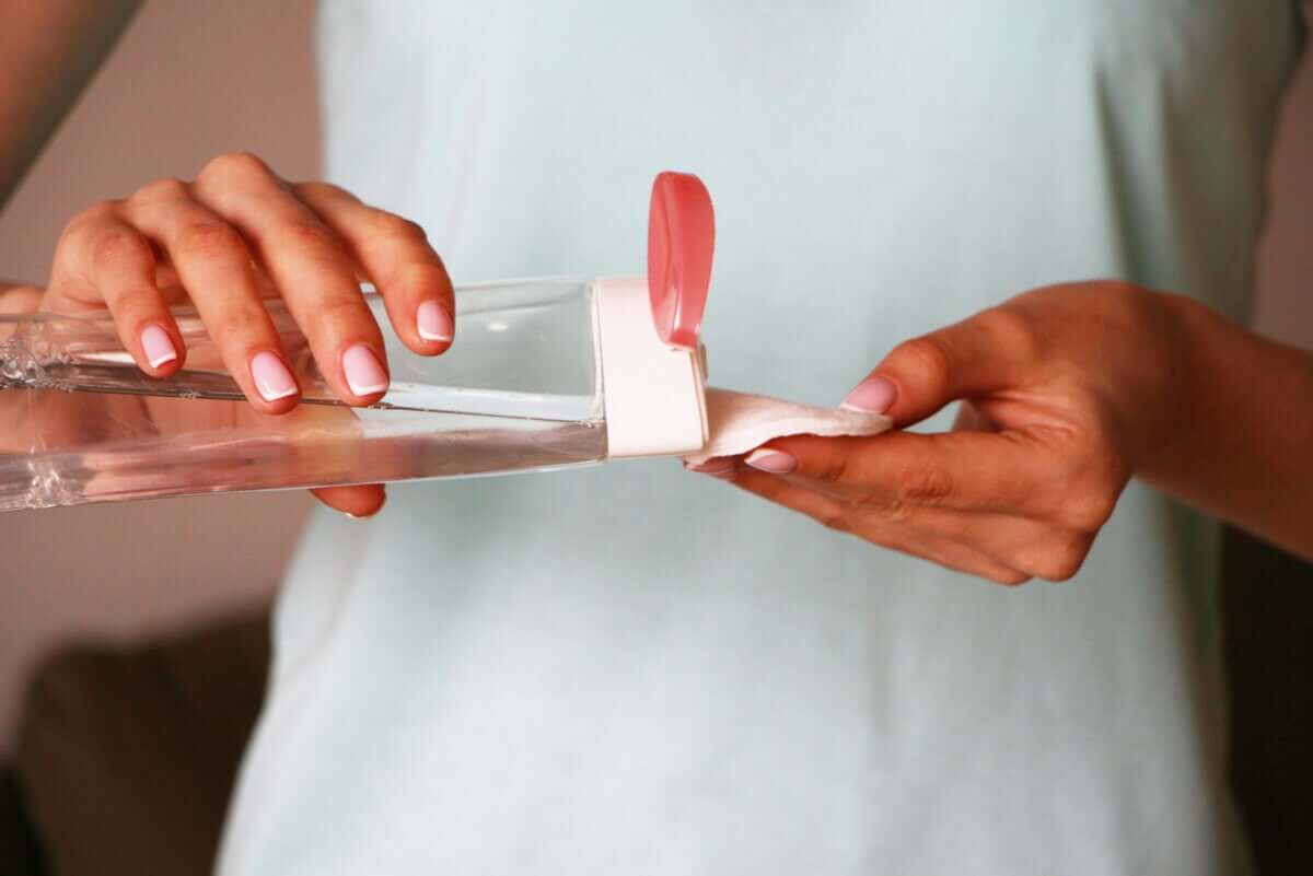 Une femme met de l'eau micellaire sur un coton.