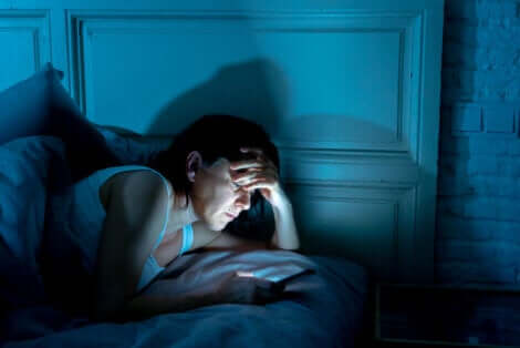 Une femme qui regarde une tablette dans son lit la nuit. 