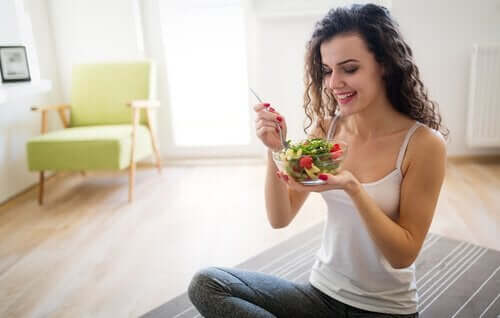 Une femme mange une salade.