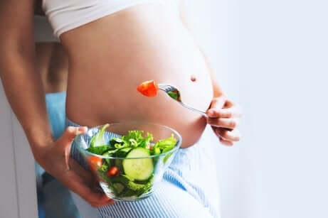 Ventre d'une femme enceinte avec une salade.