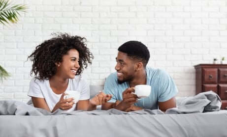 Un couple au lit avec une tasse de café. 