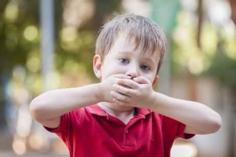 Un enfant qui se couvre la bouche. 