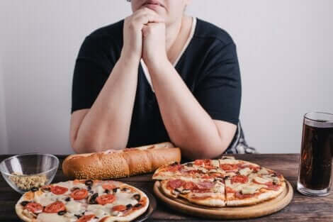 Une femme anxieuse devant deux pizzas et un coca cola. 