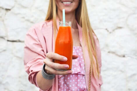 Une femme qui tient une bouteille de jus de carottes dans sa main. 