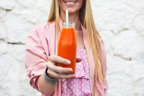 Une femme qui tient une bouteille de jus de carottes dans sa main.
