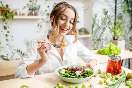 Une femme qui mange une salade en souriant. 
