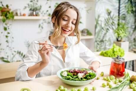 Une femme qui mange une salade en souriant.