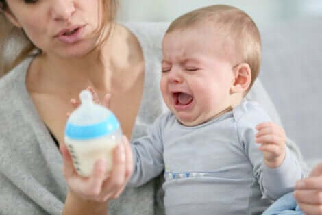 Un bébé qui pleure devant son biberon.