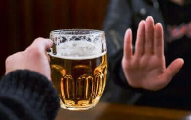 Une main qui dit non à un verre de bière. 