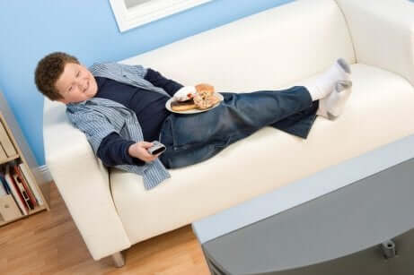 Un enfant devant la télévision qui mange des sucreries.