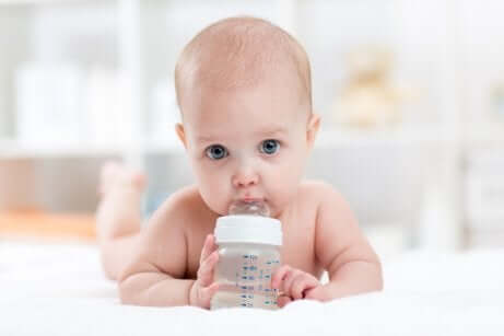 Un bébé qui boit de l'eau dans un biberon. 