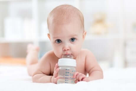 Un bébé qui boit de l'eau dans un biberon.