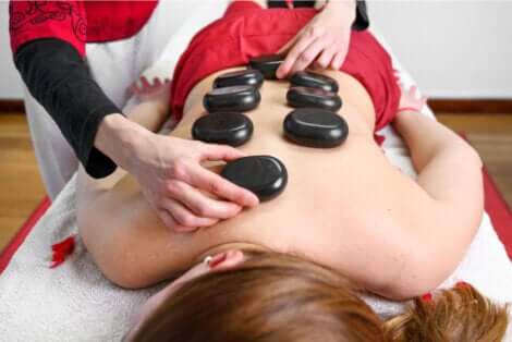 Massage aux pierres chaudes sur le dos d'une femme.