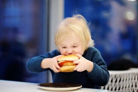 Un enfant qui mange un hamburger. 