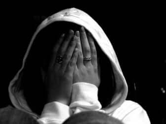Une personne anxieuse qui se cache derrière ses mains. 