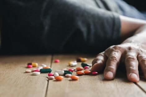 Une personne allongée avec des médicaments par terre. 